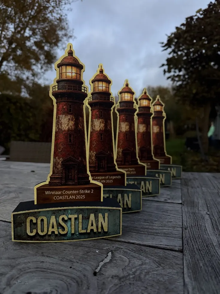 Printed lighthouse trophies for CoastLAN 2025 lined up on a wooden table